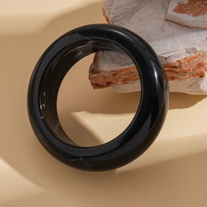 Detailed close-up of a polished black resin geometric bangle with natural marble textures