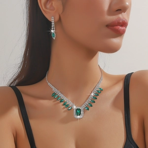 Detailed view of silver necklace and earrings set with emerald green square crystals