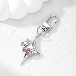 Silver star keychain with a pink heart gemstone pendant on a textured white background