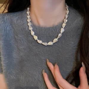 Close-up of natural white baroque pearl necklace worn on a grey knit sweater