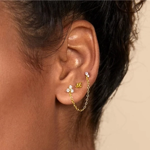 Close-up of a gold-plated snake and lightning bolt cartilage earring set on the ear