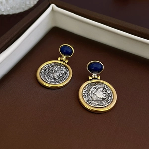 Detailed close-up of coin earrings featuring a blue gemstone and engraved portrait relief
