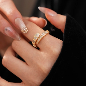 Close-up of golden snake ring set with white zircons on a model's finger