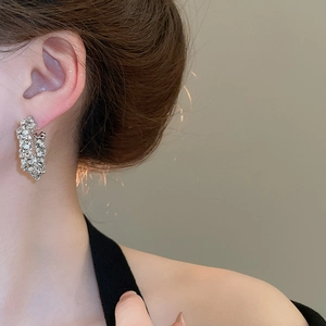 Close-up of sparkling silver star hoop earrings with crystals worn by a model