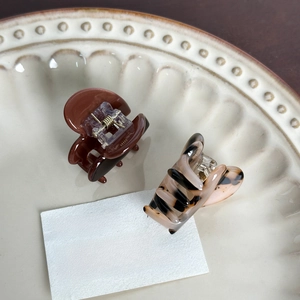 Elegant acetate heart hair clips in amber and tortoiseshell patterns on ceramic tray