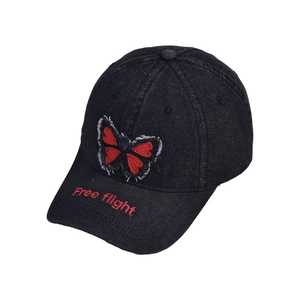 Close-up of black denim baseball cap with red butterfly embroidery and Free flight text