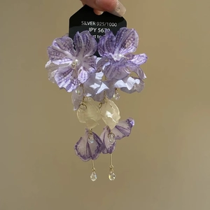 Detail of fabric flower earrings with purple petals, pearls, and 925 silver markers