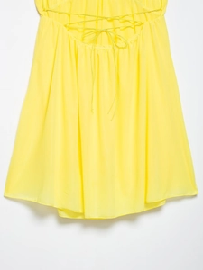 Détail macro de la robe en mousseline jaune vif avec lien à nouer délicat
