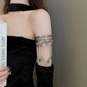 Close-up of silver boho arm cuff featuring textured metal band and coin tassel chains