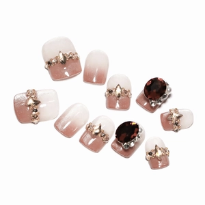 French ombré press-on nails with brown rhinestones and pearls on a white background