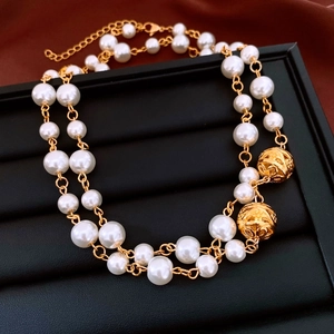 Detail of double-layer pearl necklace with golden hollow spheres and adjustable lobster clasp