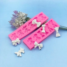 Detailed view of pink silicone bow mold with finished white resin bow pieces on blue background