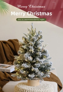 Desktop mini Christmas tree with warm LED lights and flocked snow on a wooden base