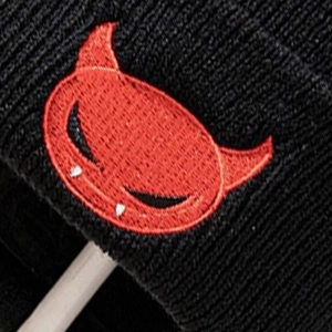 Black knit beanie featuring a red little devil embroidery with horns in a street style look