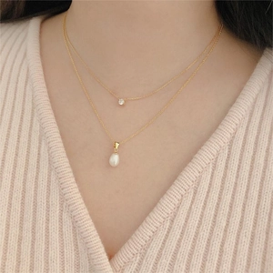 Close-up of double-layer gold necklace with zircon and teardrop pearl on model
