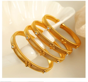 Detail of 18k gold plated snake bone bracelets with clover relief and white zircon inlay