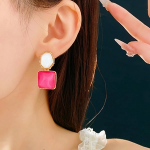 Detail von quadratischen rosa und weißen geometrischen Ohrringen mit Goldrand am Model