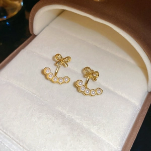 Detailed macro view of 18k gold plated bow earrings with white pearls on velvet display
