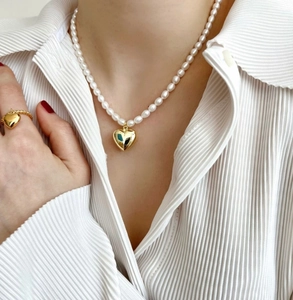 Detail of elegant gold heart pendant pearl necklace and matching rope ring set