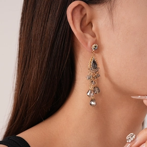Gros plan détaillé de boucles d'oreilles vintage à pampilles dorées portées par un modèle