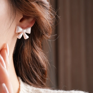 Macro shot of a pearlescent pink bow earring worn on a model with warm lighting