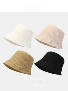 Detail showing four minimalist bucket hats in white, beige, brown, and black bubble fabric