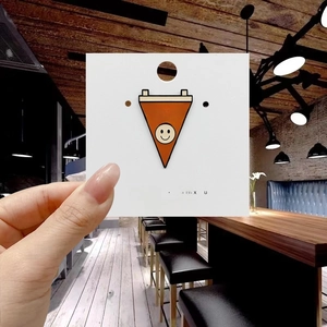 Detail of Happy Camper orange pennant enamel pin on white display card for camping enthusiasts