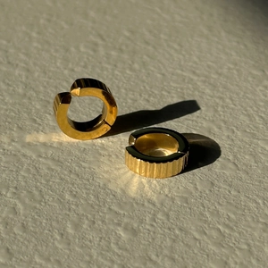 Macro shot of gold stainless steel ear cuff with vertical striped texture and hinged design