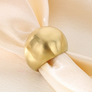 Close-up of wide gold ring with matte finish resting on luxury champagne silk fabric