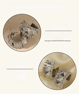 Detailed close-up of polished silver stainless steel C-shaped earring with pyramid studs