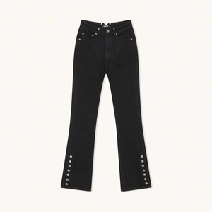 Close-up of side metal buttons and split hem on these black flared denim pants