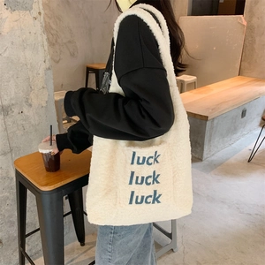 Close-up of plush lamb wool tote bag featuring blue luck letter embroidery and soft texture