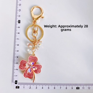 Detailed scale view of a pink rhinestone four-leaf clover keychain with gold lobster clasp