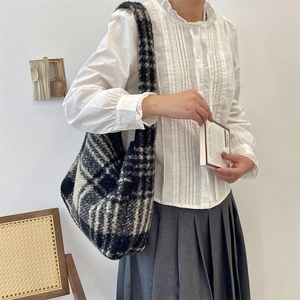 Close-up of black and white plaid wool tote bag with soft plush texture for winter