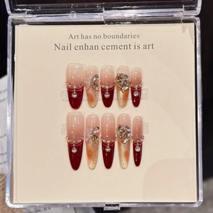 Handmade almond press-on nails with wine red gradient, gold glitter, and rhinestones