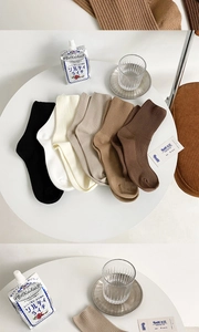 Flat lay of ribbed crew socks in earth tones like khaki, brown, and grey on a white table