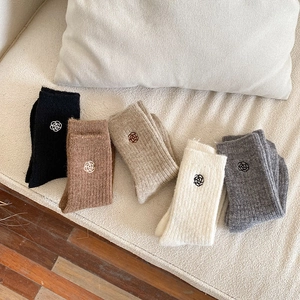 Close-up of five pairs of warm knitted socks with delicate flower embroidery on the cuffs