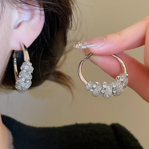 Detail of silver hoop earrings featuring five shimmering textured decorative spheres