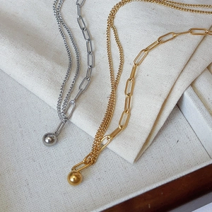 Detail of mixed paperclip and ring chain necklace with polished gold and silver spherical charms