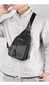 Close-up of stylish black and grey sling bag with earphone port on male model