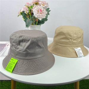 Flat lay of minimalist cotton bucket hats in gray-brown and khaki with stylish side labels