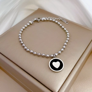 Gros plan d'un bracelet en acier titane avec pendentif cœur noir et blanc sur un écrin