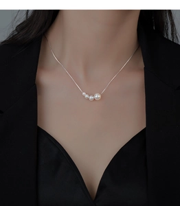 Elegant four-pearl gradient necklace on model neck with minimalist silver chain style