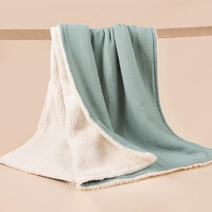 Detail of sage green muslin baby blanket showing soft sherpa fleece lining and cotton texture