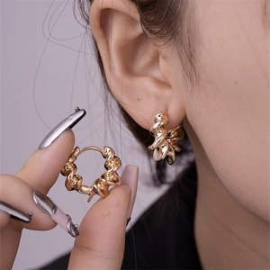 Detailed macro view of golden twisted hoop earrings featuring a spiral metal texture