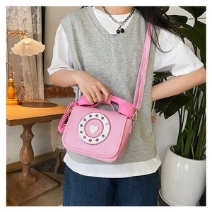 Stylish pink novelty retro telephone shaped crossbody bag shown in a cozy lifestyle indoor setting