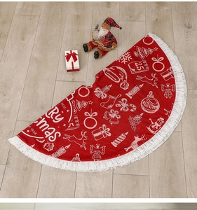 Detail of red Christmas tree skirt with white tassels and Merry Christmas print on wood floor