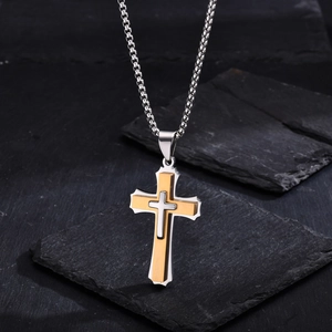 Macro shot of tiered gold and silver cross pendant on rugged square chain and black slate