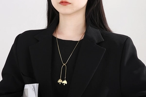 Détail du collier avec pendentif arbre de vie doré porté sur un blazer noir élégant