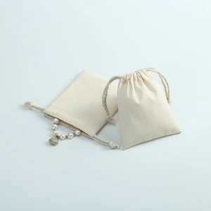 Detail view of two beige cotton linen drawstring bags with pearl necklace storage